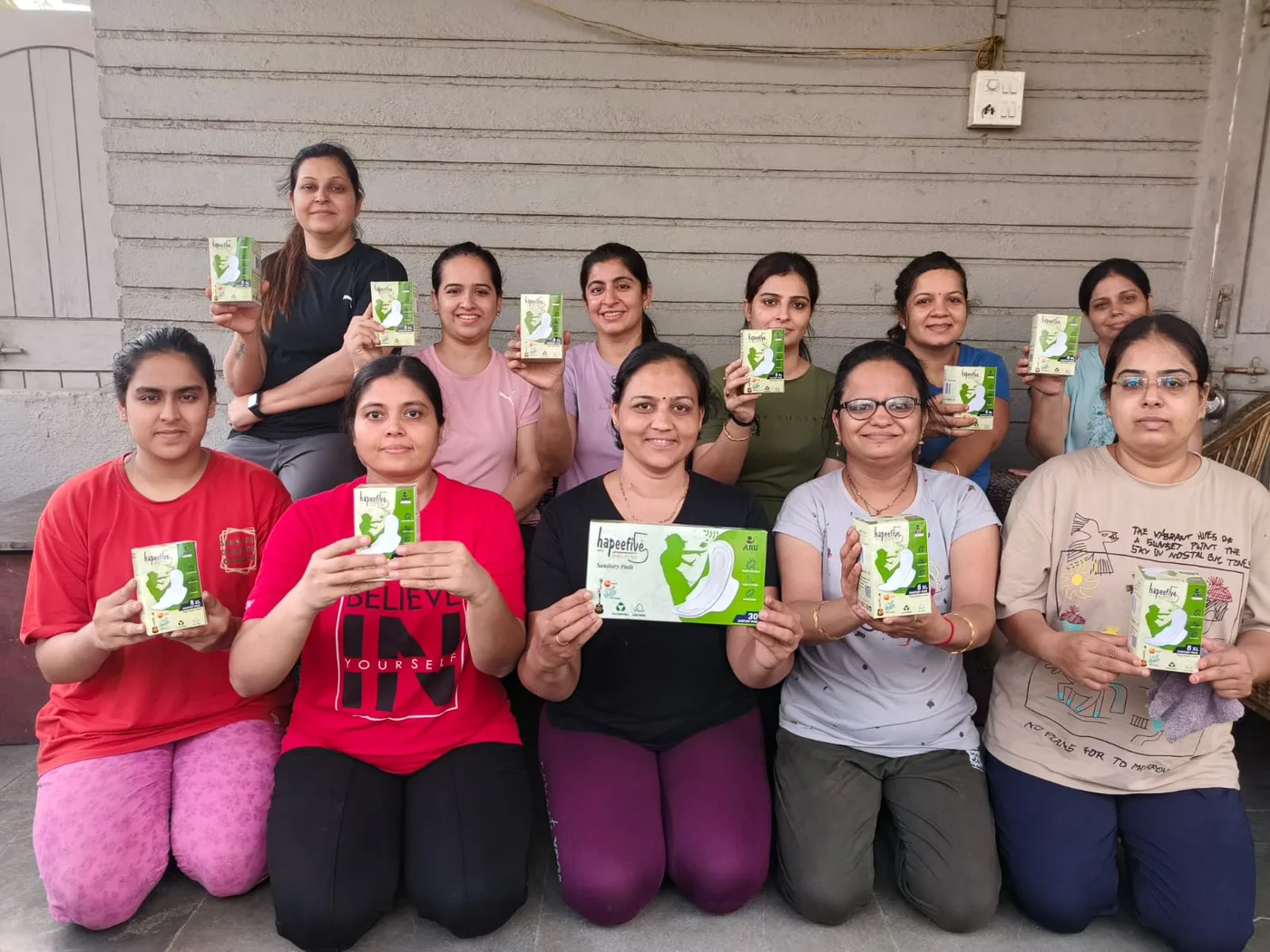 Hapeefive team members holding Hapeefive sanitary pad packs